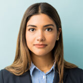Closeup of young female professional making eye contact against colored background